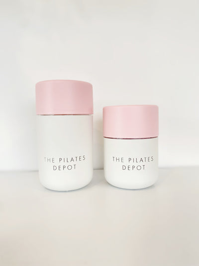 two white base and pink lidded cups with the pilates depot engraved. one is larger than the other