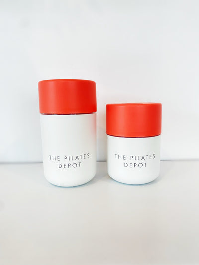 two cups with red lids and white bases in two sizes. both have the pilates depot engraved