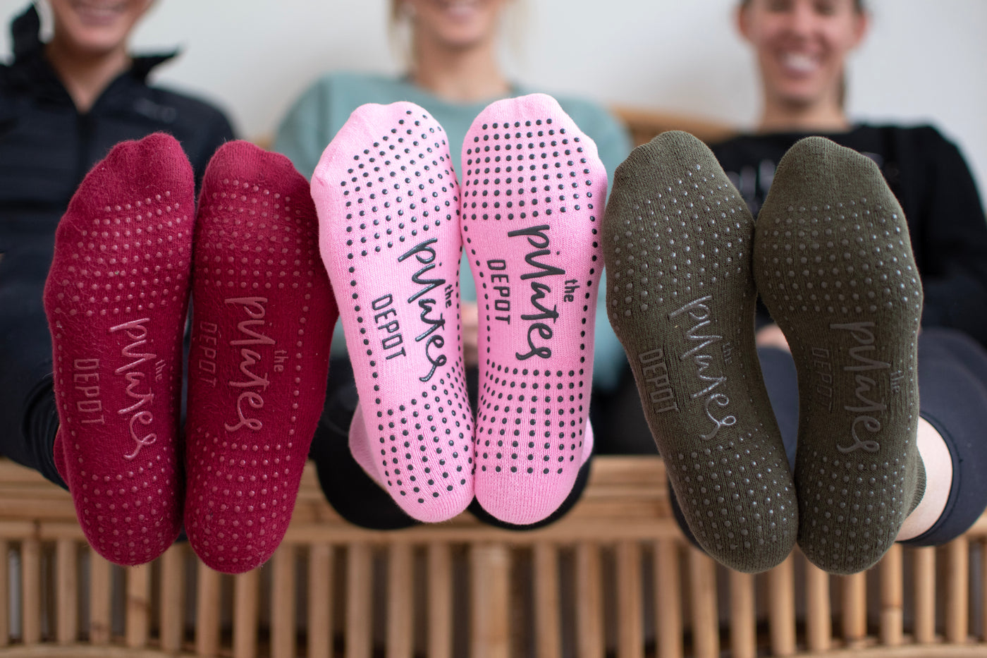 three pairs of feet wearing TPD Store Grippy Socks. Red Wine, Blush ink and Kahki colours.