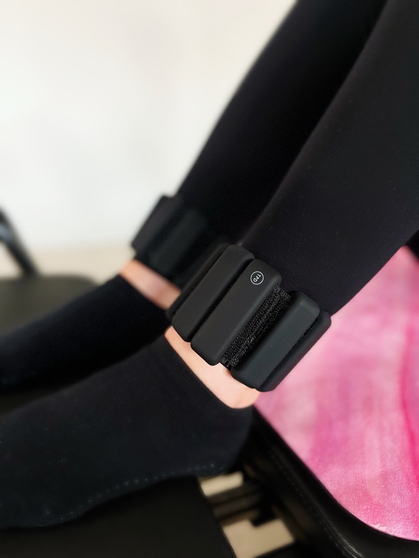 pair of black tpd store ankle weights on legs bent and resting on reformer