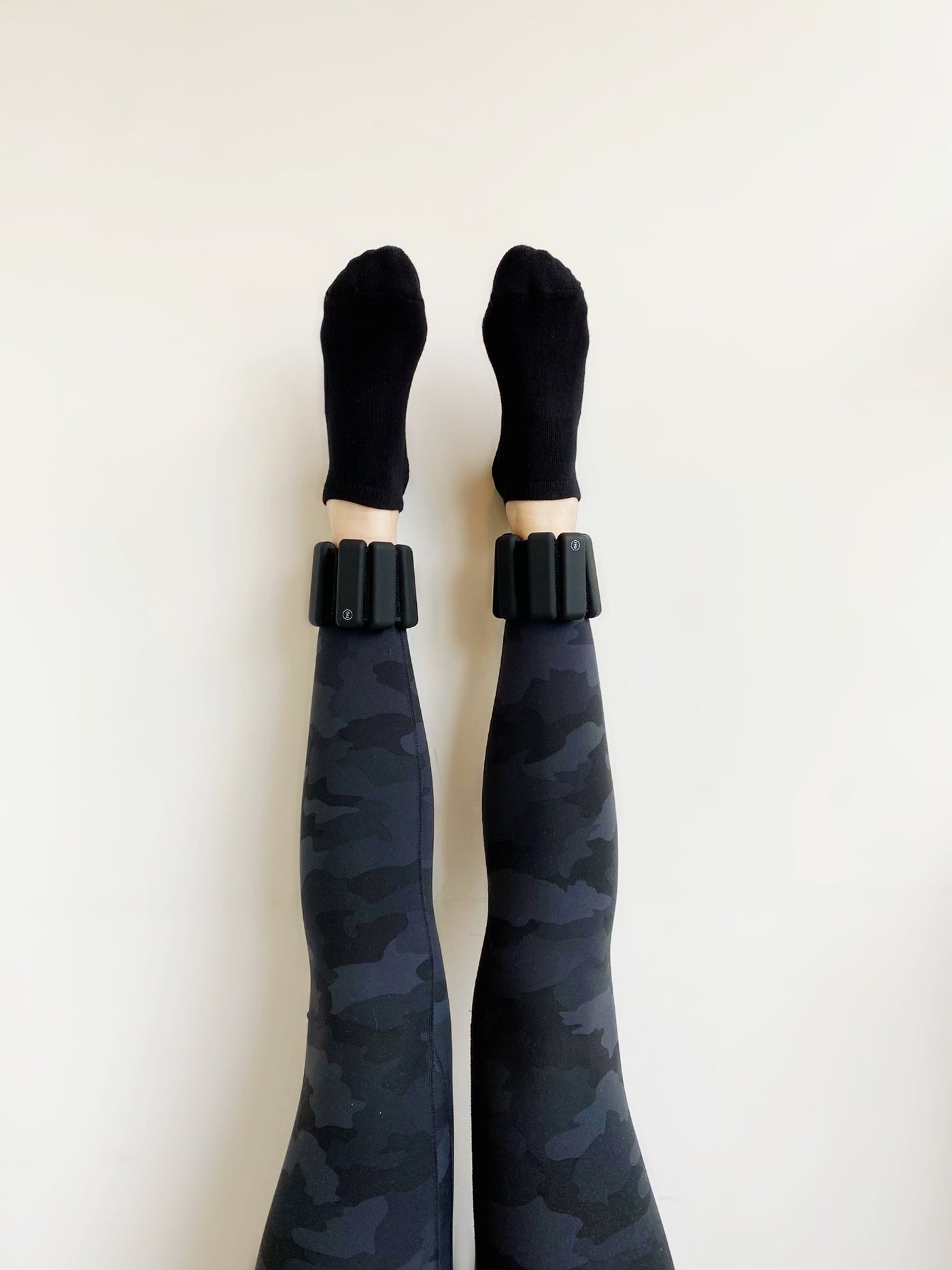 legs arised against a wall with a pair of tpd store black ankle weights on