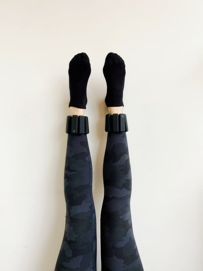 legs arised against a wall with a pair of tpd store black ankle weights on