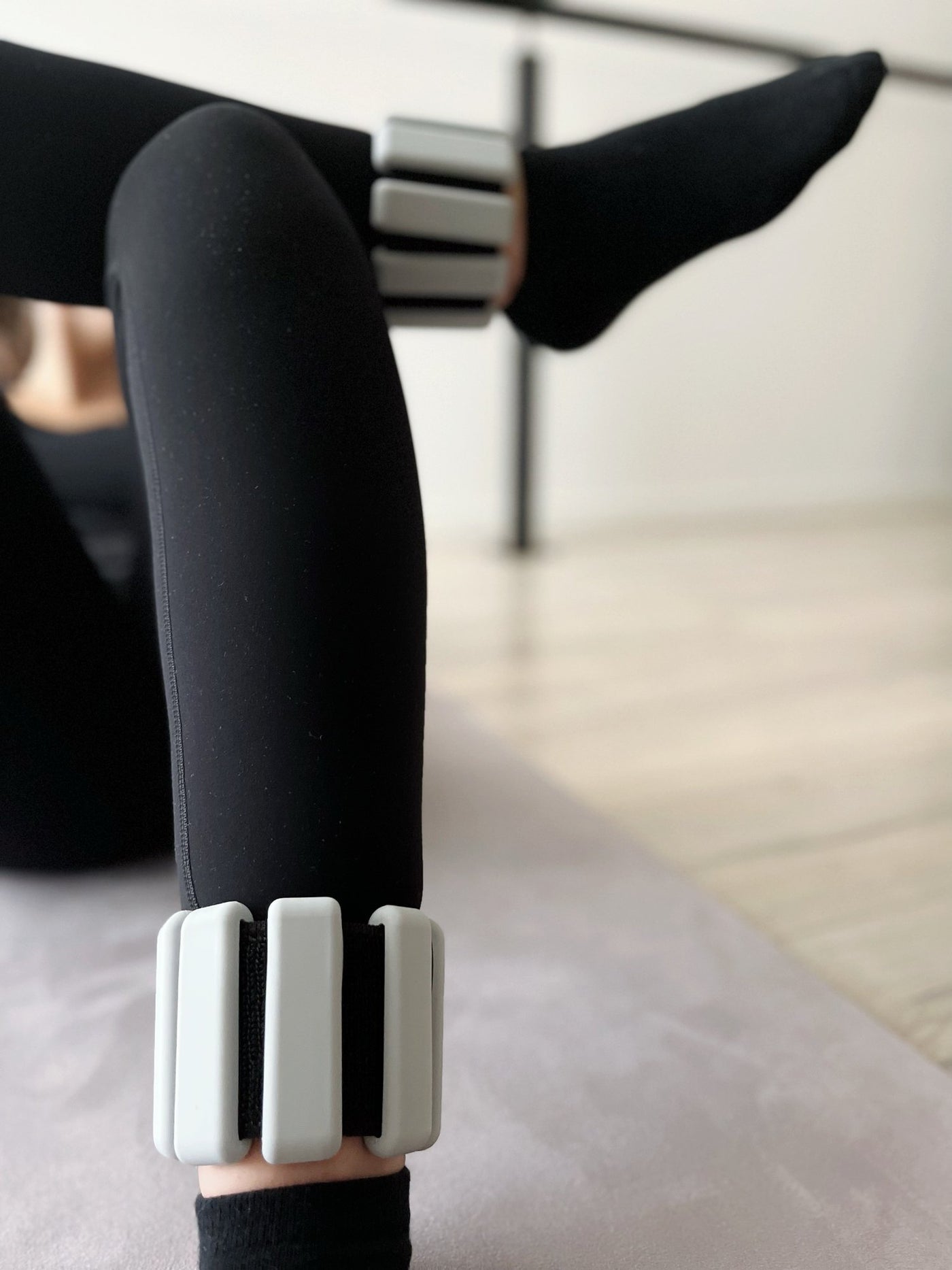 woman with crossed legs lying on her back wearing a pair of grey tpd store ankle weights