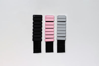 one of each colour of tpd store ankle weights, black, pink and grey unrolled on a white background
