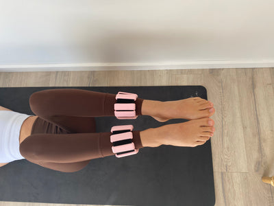 pair of td store pink ankle weights on womans legs while they lie on back with legs up bent and the knees