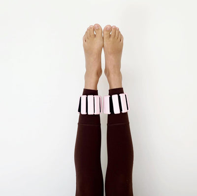a pair of tpd store pink ankle weights worn on legs that are raised in the air