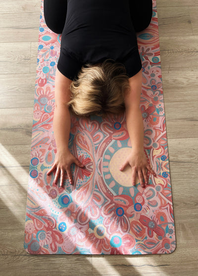 woman in childs pose from above resting on you are my sunshine tpd store eco friendly yoga mat