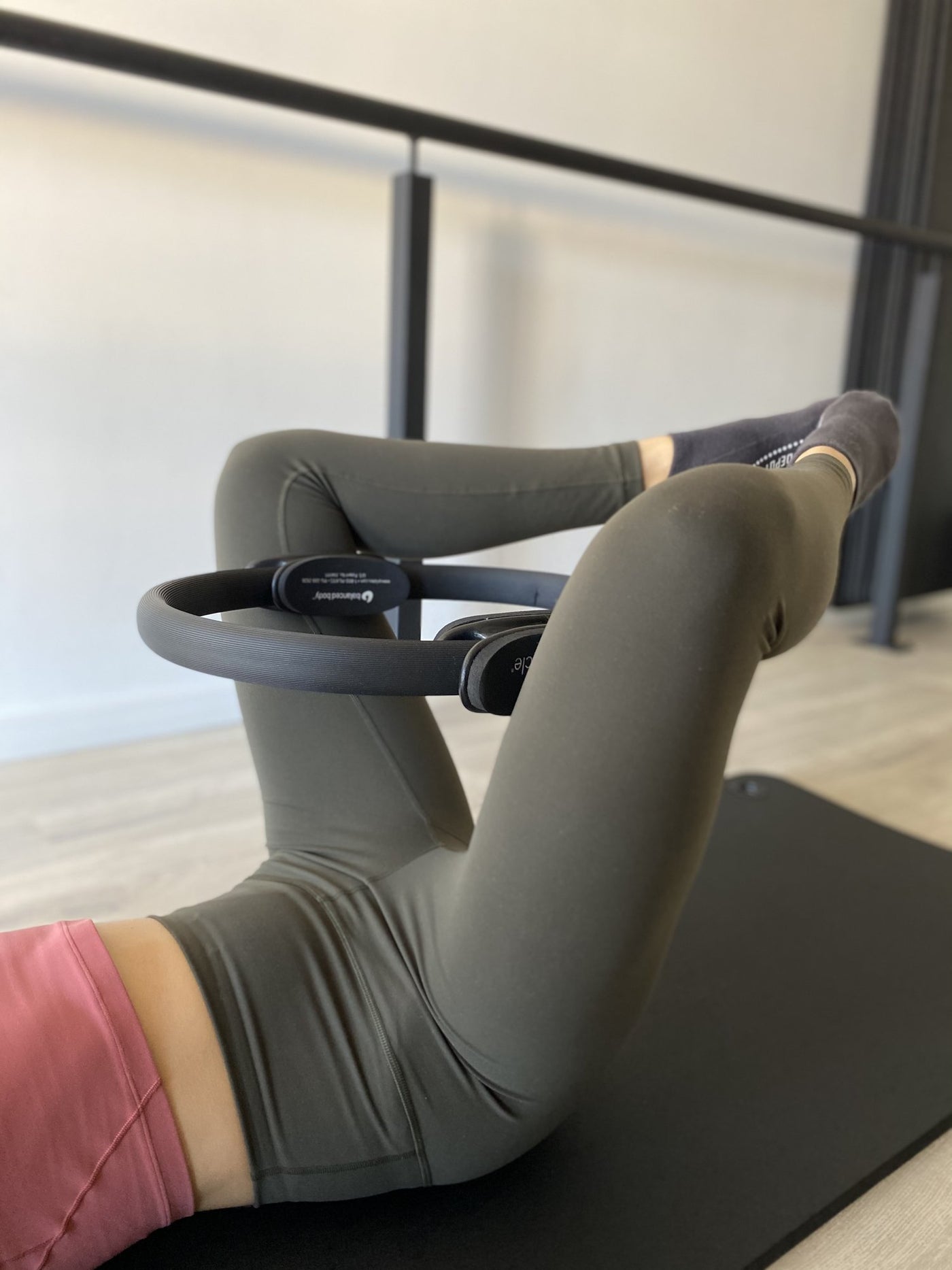 woman lying on her back with tpd store black pilates ring between her raised knees