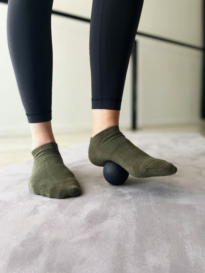 woman standing with a black tpd store trigger ball under her right foot