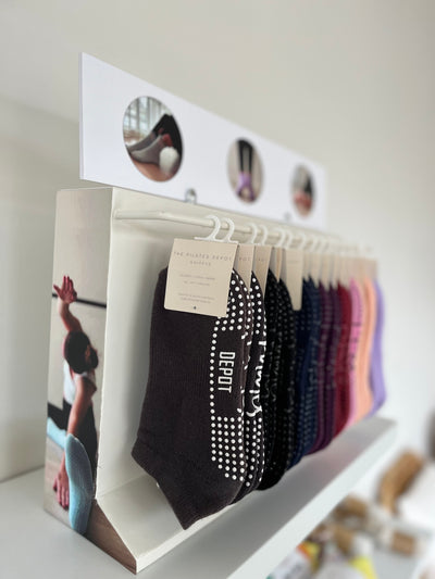 shelf with a tpd store grippy sock wholesale display rack holding multiple pairs of socks in many colours