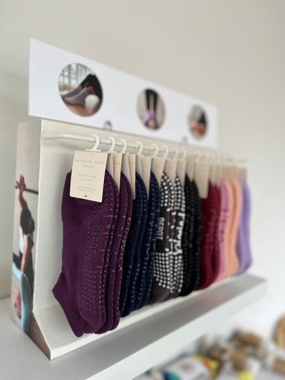 A rack of grippy socks used for pilates and yoga. Rack is sitting on a studio or shop shelf.