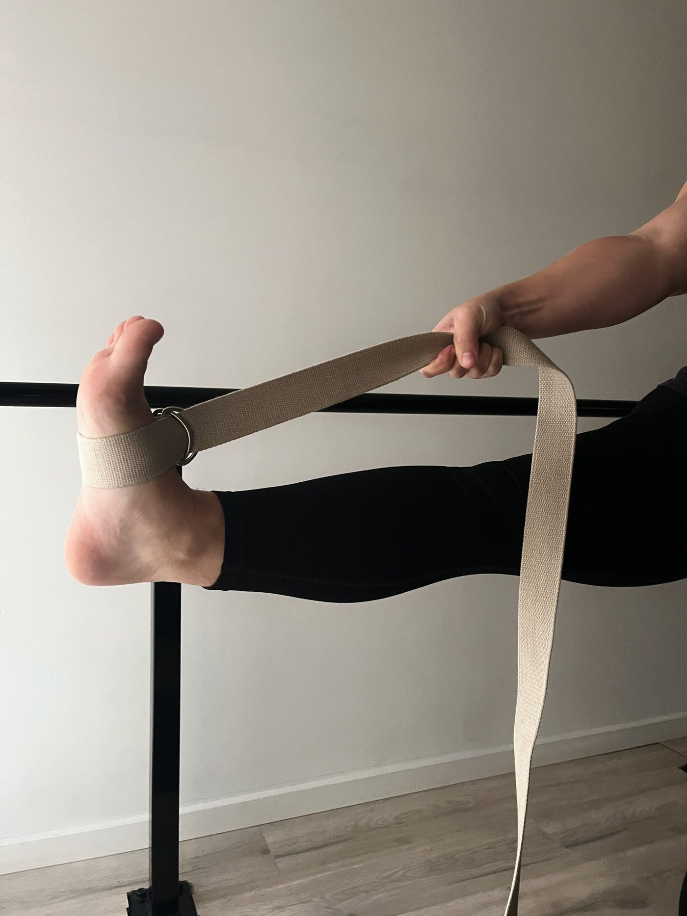 woman with tpd store organic cotton strap around her lifted leg being pulled towards hip height