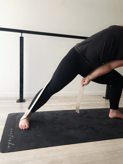 woman holding tpd store organic cotton strap around foot and leaning into a side lunge