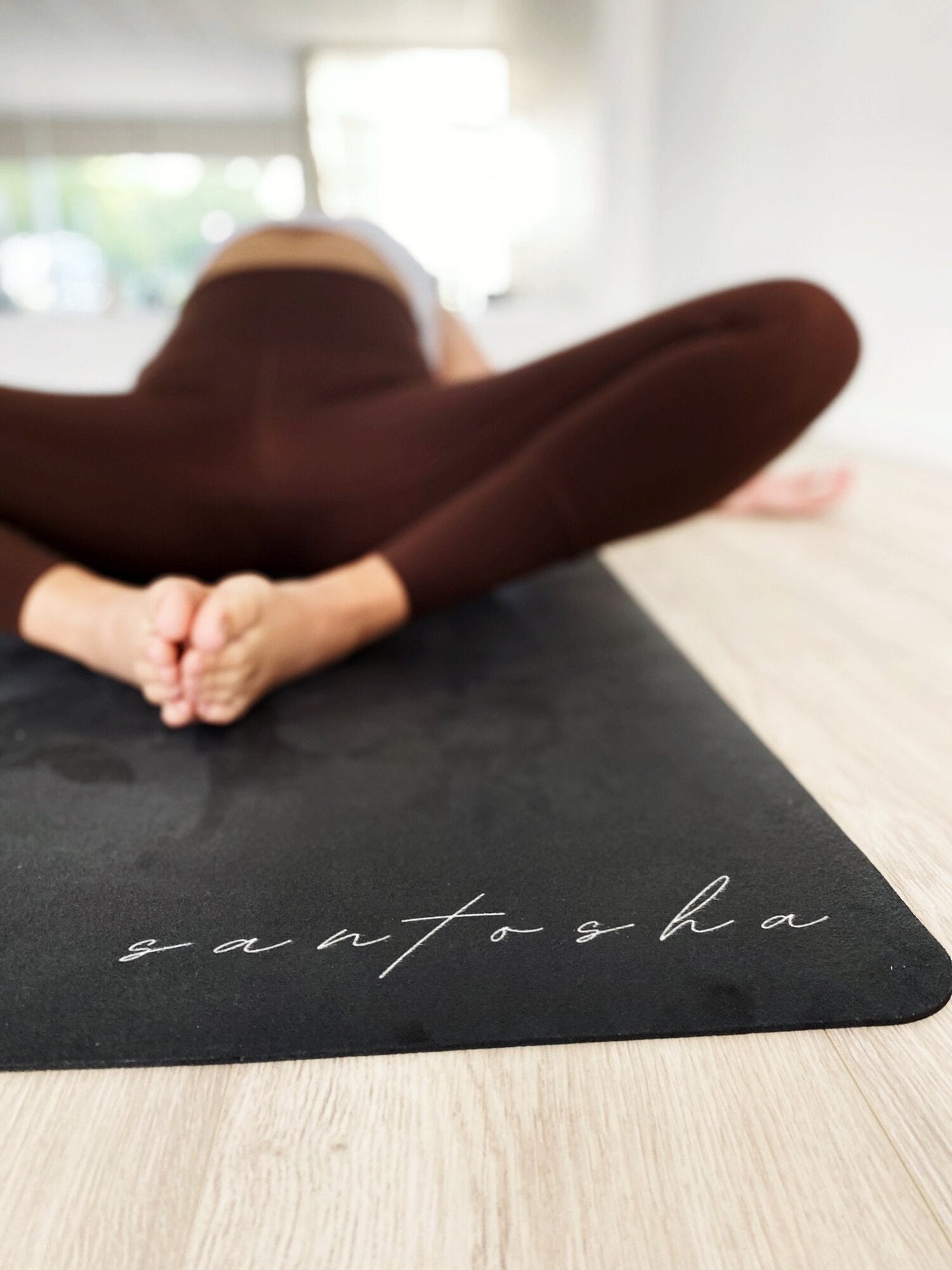 woman lying on her back on the black santasha tpd store eco friendly yoga mat