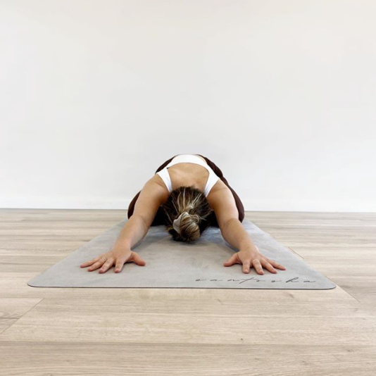 woman in childs pose lying on tpd store eco friendly yoga mat in stone colour