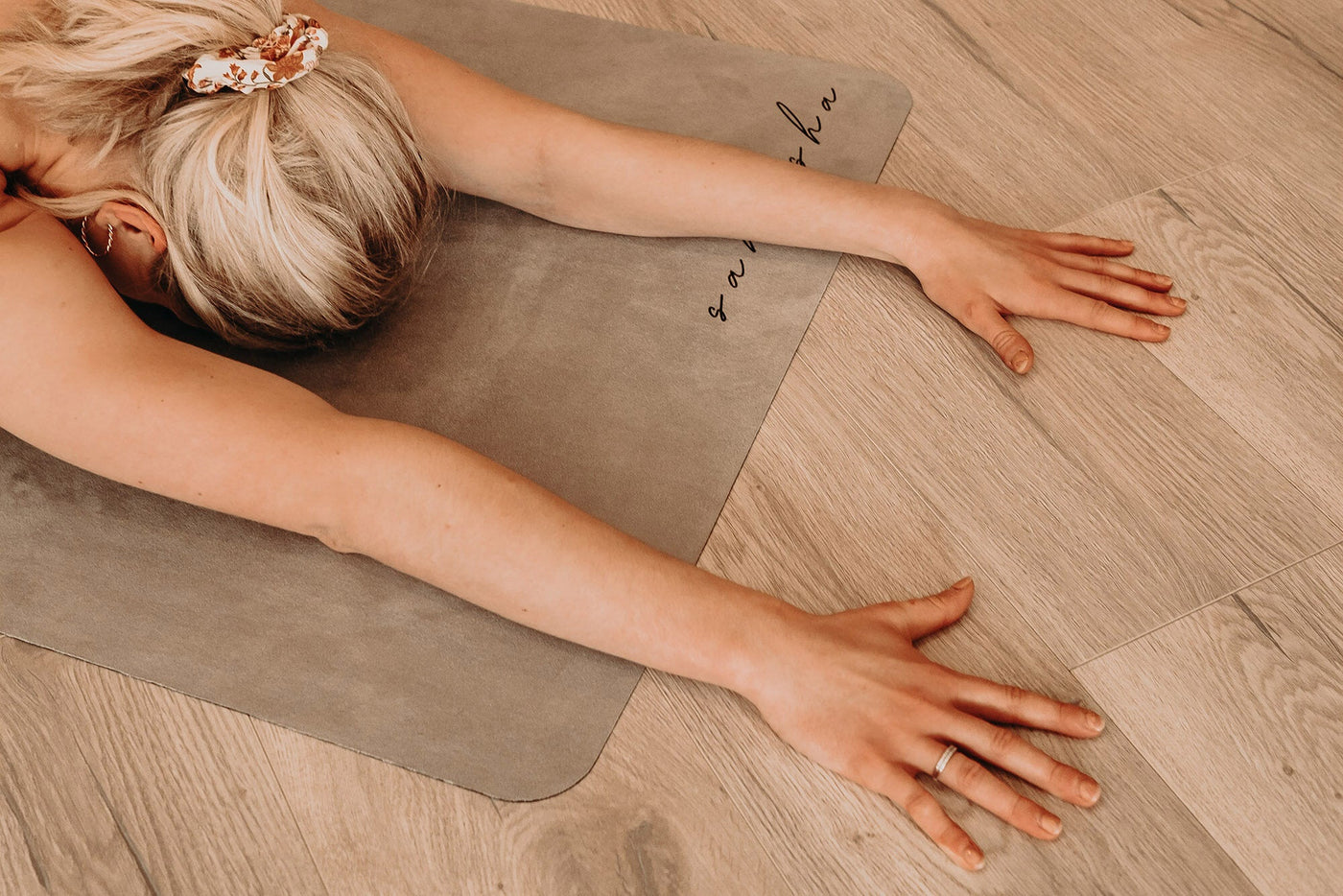 woman in childs pose with hands byond the edge of the stone coloured tpd store edo friendly yoga mat