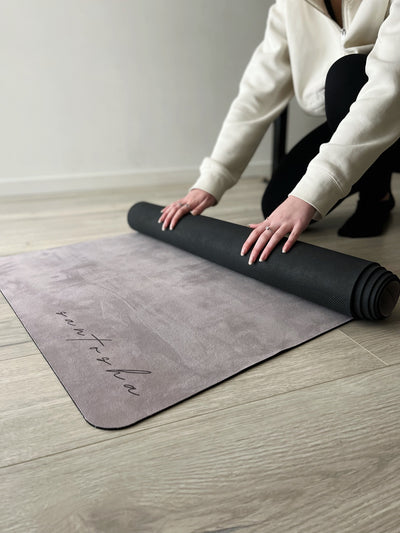 woman rolling up stone coloured santasha eco friendly yoga mat from tpd store