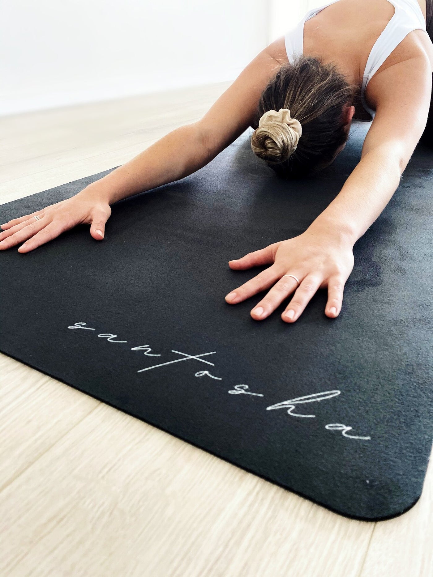 woman in childs pose on a black santasha tpd store eco friendly yoga mat