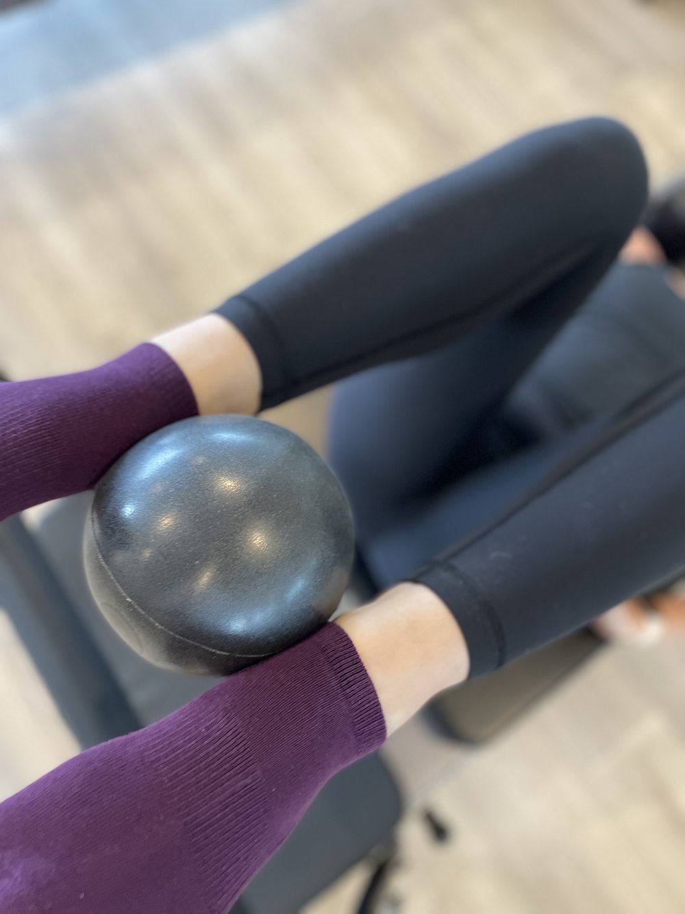 woman lying on her back with legs raised and knees bent holding a tpd store chi ball between her ankles