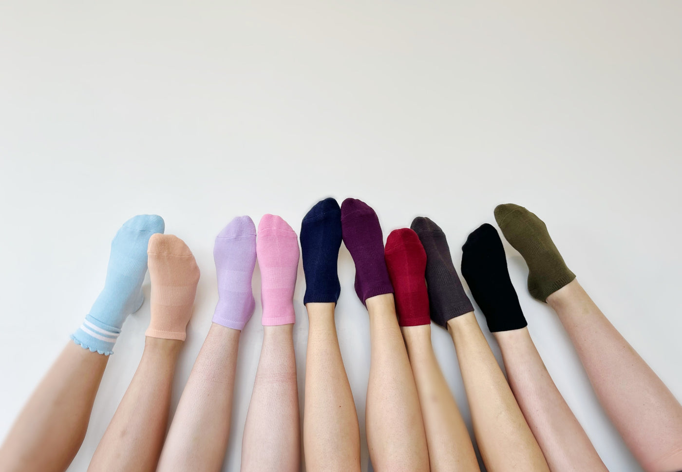 feet wearing TPD Store grippy socks in different colours resting on a white background