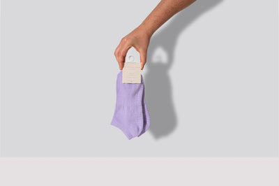 hand holding a pair of TPD Store Grippy socks in French Lilac low rise