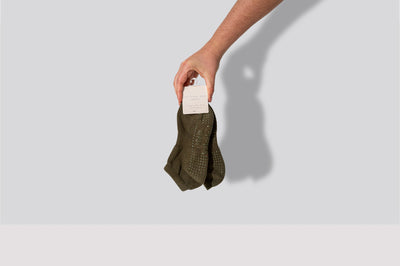 hand holding a pair of tpd store kahki low rise grippy socks