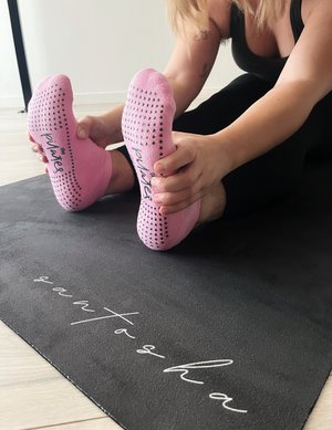 woman sitting leaning forward holding feet wearing tpd store pink blush low rise grippy socks